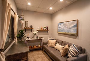 room with shelves on the wall, a gray couch, and a painted horse mural